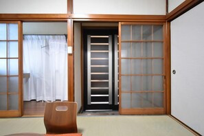 A traditional Japanese room with sliding doors, a tatami mat floor, and a wooden chair. - Bunka 1 chome (Tokyo)