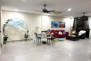 A living room with a dining table, chairs, a red sofa, and a ceiling fan. - Santorini 3000sqft Townvilla, rooftop BBQ, 5BR, 13pax (Puchong)