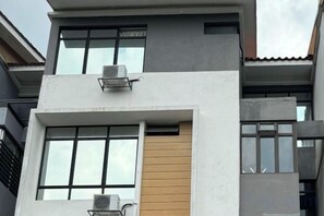 Un bâtiment moderne doté de nombreuses fenêtres, de climatiseurs et d’un toit plat.