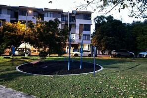 Un espace paysager agrémenté d’un parterre circulaire, d’un banc et d’un immeuble à plusieurs étages en arrière-plan.