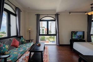 A room with a sofa, a bed, a television, and a view of the outside. - Sila Vana Villa - Private 7BRs Pool Villa My Khe Beach Da Nang (Da Nang)