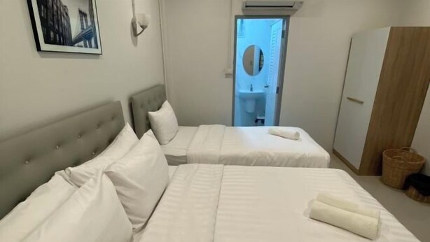 A hotel room with two beds, a wardrobe, a framed picture on the wall, and a bathroom visible through an open door. - TWOHOME Near Nimman (Chiang Mai)
