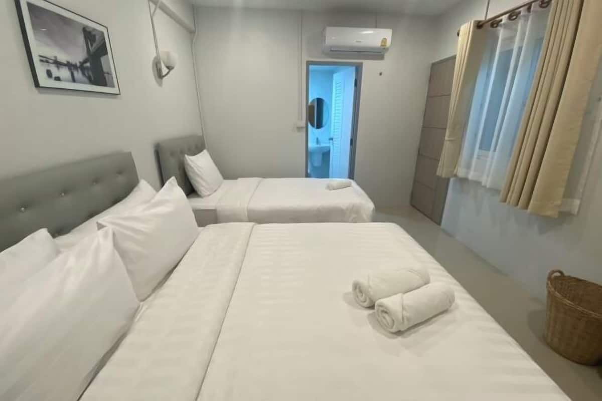 A hotel room with two beds, a large window, an air conditioning unit, and a framed picture on the wall.