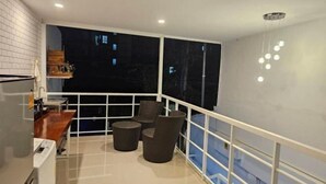 A balcony with a view of the night sky, a white railing, and a seating area with two chairs and a small table. - TWOHOME Near Nimman (Chiang Mai)