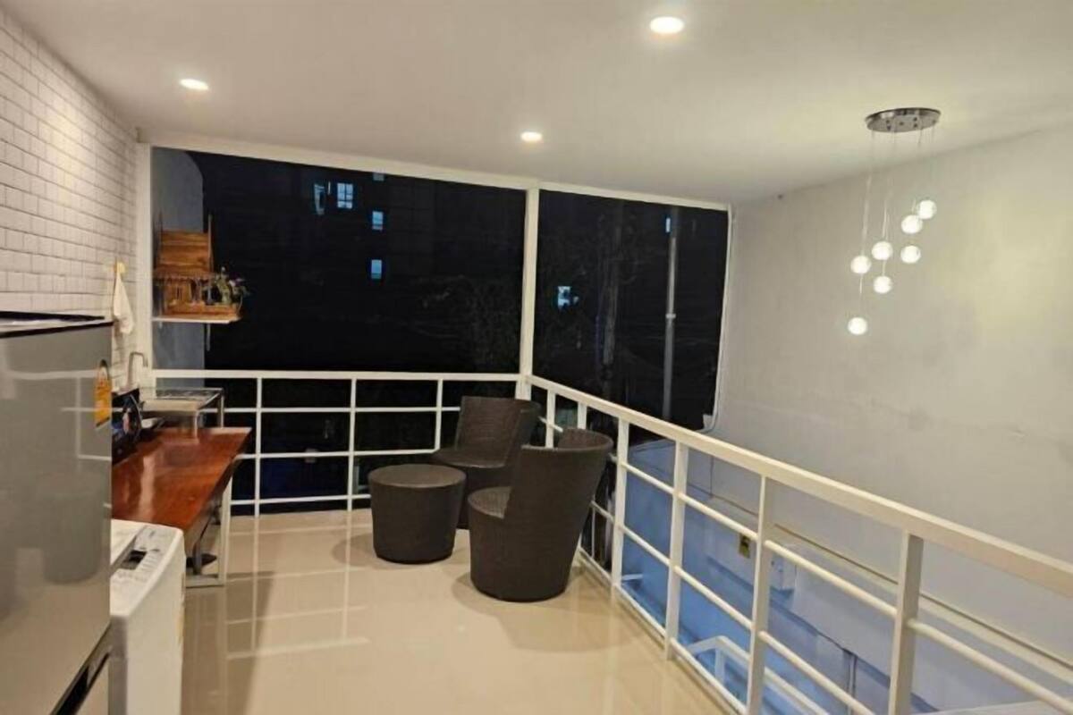 A balcony with a view of the night sky, a white railing, and a seating area with two chairs and a small table.