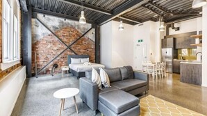 A modern interior with a gray sofa, a small round table, and a brick wall.