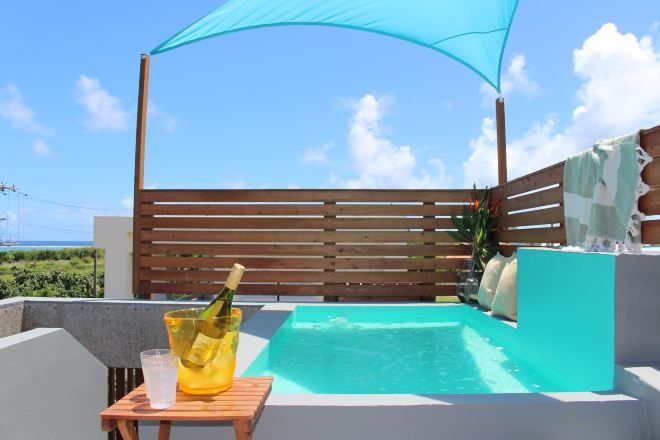 A pool area with a wooden deck, a lounge chair, and a bottle of champagne.