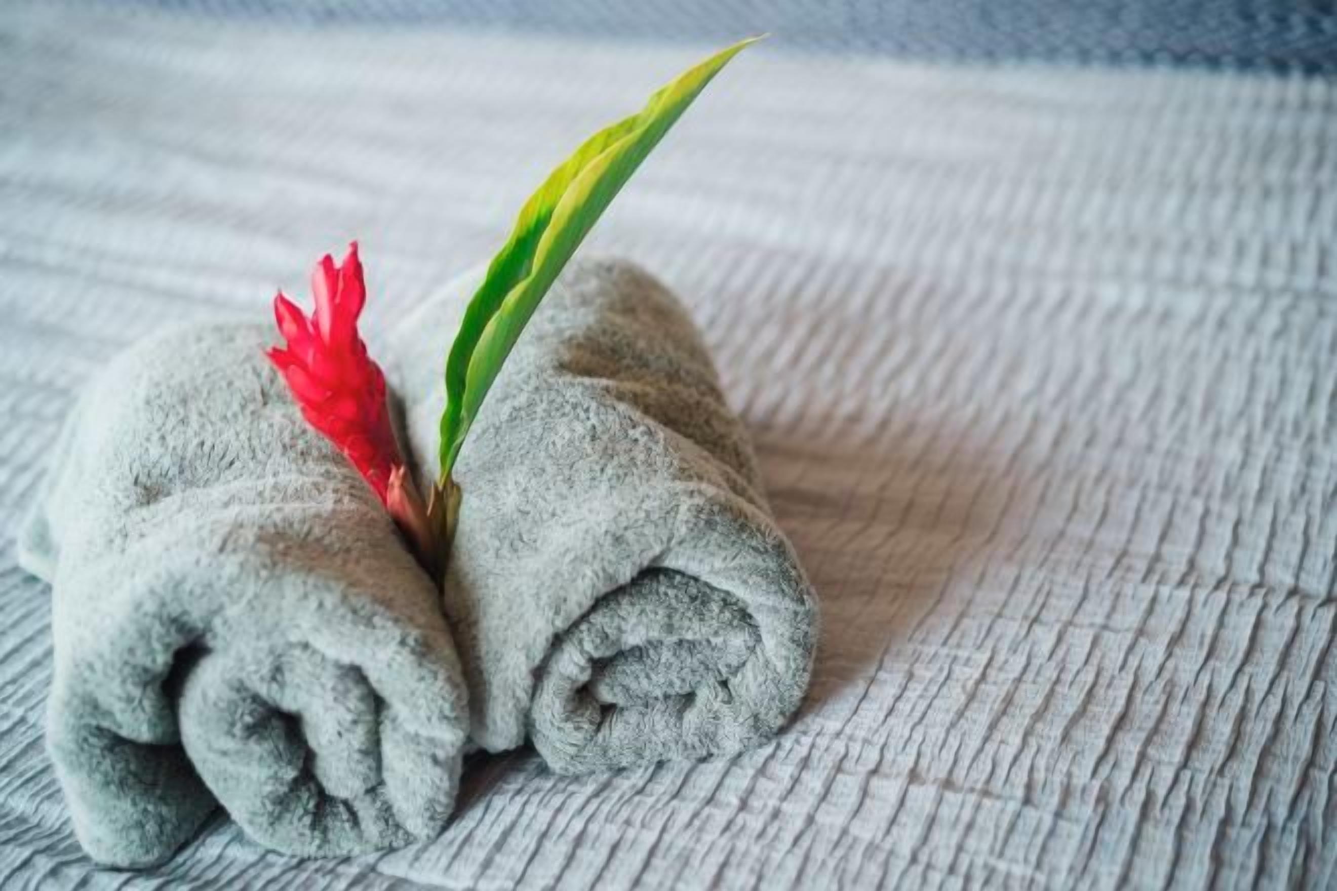 A towel with a red flower and a green leaf placed on a textured surface.