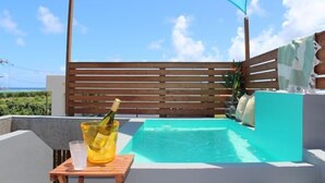 Een privé jacuzzi buiten, met een houten terras en een blauw zonnescherm, met uitzicht op een prachtig landschap.