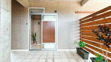 Un interior modern amb una porta corredissa que condueix a una habitació, una paret de lamel·les de fusta i plantes en testos.