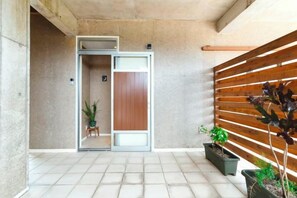 A modern interior with a sliding door leading to a room, a wooden slatted wall, and potted plants. - Ocean Palm Villa Ishigaki (Ishigaki)