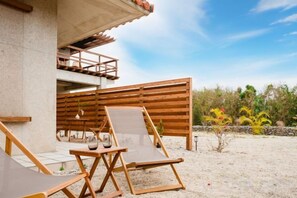 A beachside lounge area with wooden loungers and a concrete structure.