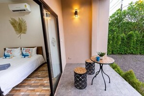 A bedroom with a bed, a window, and a small table with a plant. - Summer Sea Villa Khanom (Khanom)
