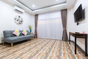 A living room with a sofa, a small table, a TV, and a patterned floor. - Summer Sea Villa Khanom (Khanom)