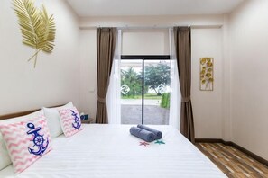 A hotel room with a bed, curtains, a view through a glass door, and a palm leaf decoration. - Summer Sea Villa Khanom (Khanom)