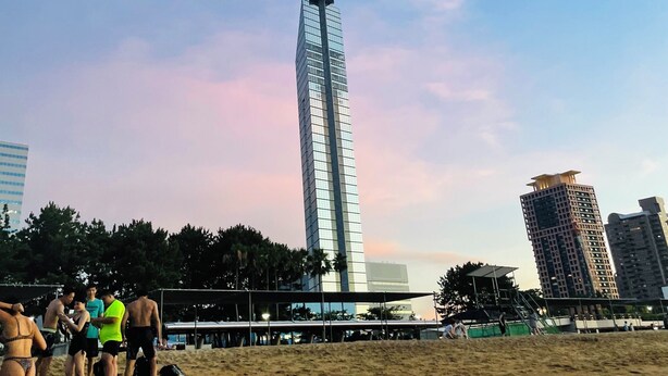 A beach with a tall, modern skyscraper in the background.