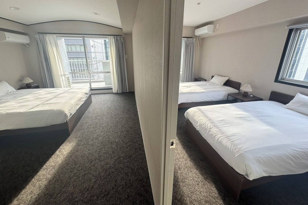 A hotel room with two beds, a large window, and a view of the outside.