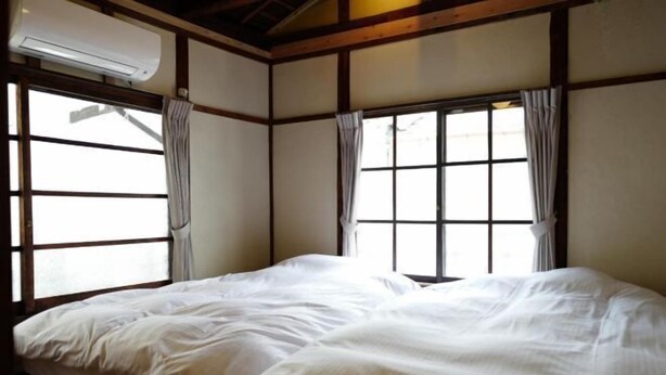 Una habitación con dos camas, vigas de madera y ventanas grandes con cortinas.