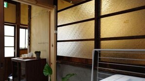 Una habitación con un armario de madera, una planta y una cama blanca con estructura metálica.