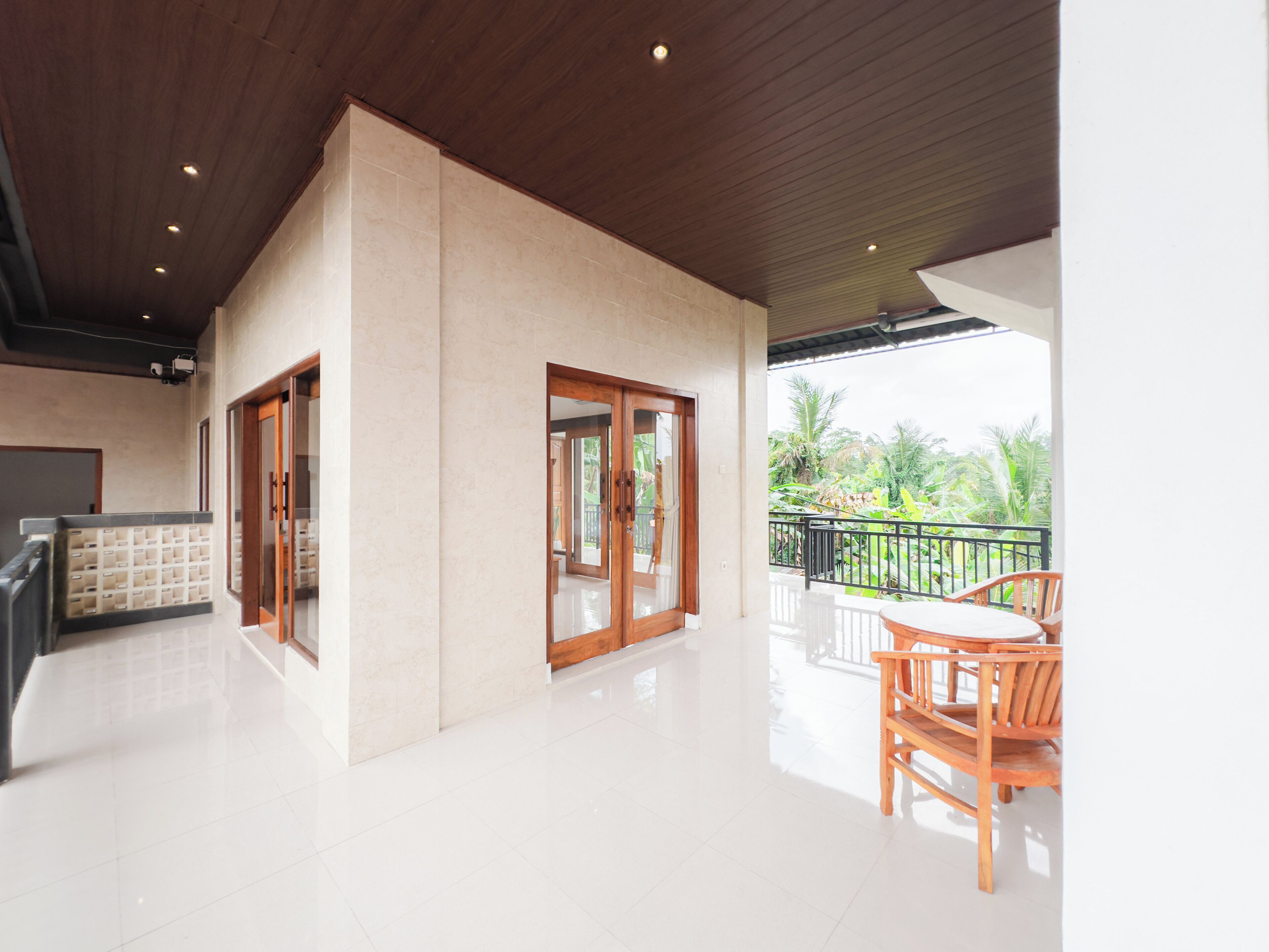 A spacious indoor area with a balcony, a wooden table, and chairs.