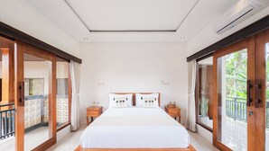 Un dormitorio espacioso con una cama grande, cabecero de madera y un balcón con vistas a zonas verdes.