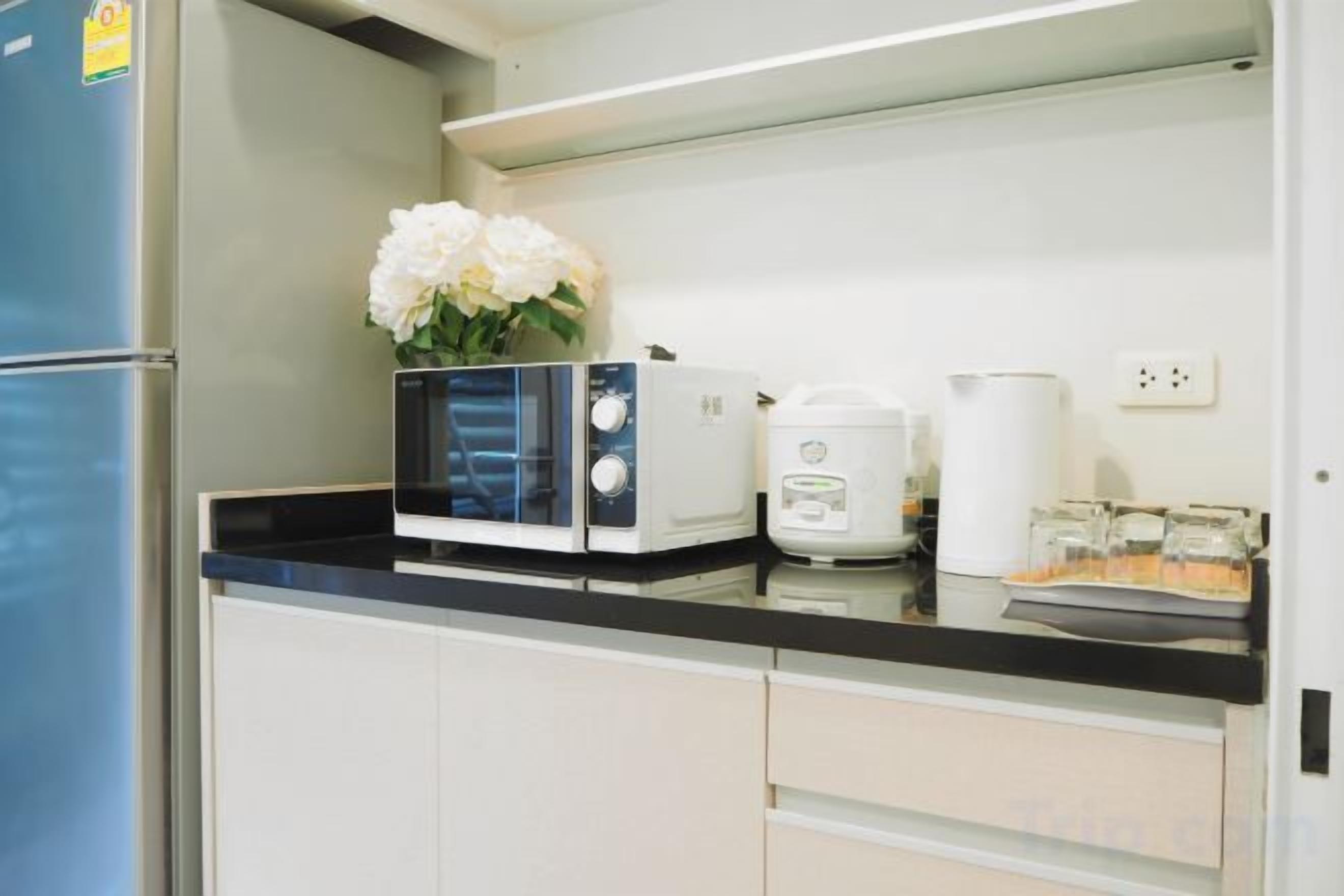 A kitchen with a microwave, toaster, and a vase with flowers on the counter.
