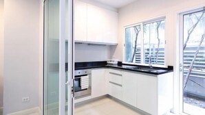 Een moderne keuken met witte kasten, een zwart aanrecht en een raam met uitzicht op bomen.