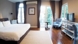 Een hotelkamer met een groot bed, een televisie, een bureau en een stoel.