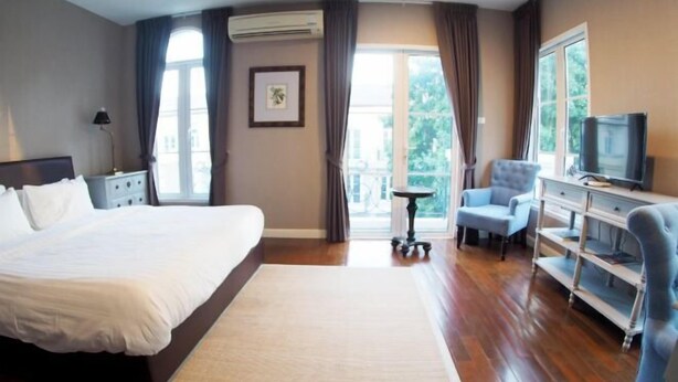A hotel room with a large bed, a TV, a desk, and a chair. - Sol Stay Sukhumvit 16 Entire House Three Bedroom & Full Kitchen (Bangkok)