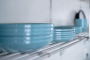 Una cocina con un estante metálico que contiene varias fuentes azules.