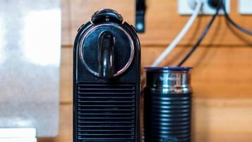 A vintage radio with a cylindrical speaker and a switch on top, placed on a wooden surface.