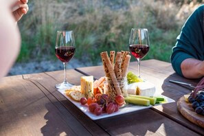 A picnic setup with a cheese board, grapes, and wine glasses on a wooden table. - Cascade Creek Retreat (Circle Hill)