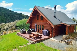 A log cabin with a deck, outdoor seating, and a chimney. - Cascade Creek Retreat (Circle Hill)