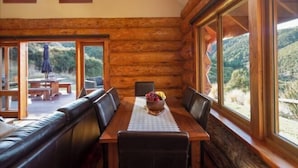Interior de una cabaña de madera con una mesa de comedor, sillas y un banco.