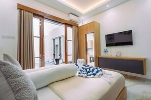 Habitación de hotel con cama, televisión, escritorio y vistas al exterior.