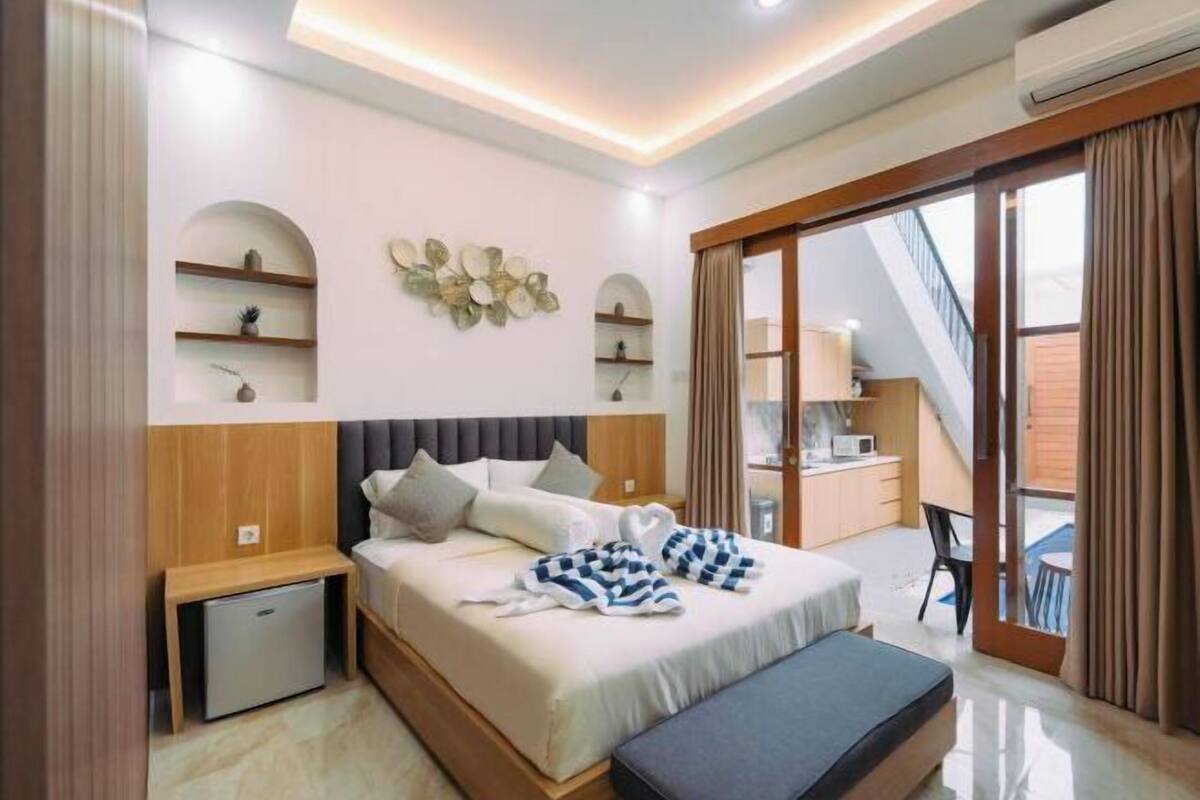Une chambre moderne avec un lit, des tables de chevet, un bureau et une vue sur l’extérieur.
