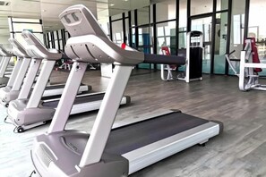 A row of treadmills in a gym with a wooden floor and large windows in the background. - Cityview MidValley Southkey 2BR+2FREE 16FL BY NATOL (Plentong)