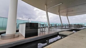 A rooftop bar with a pool, outdoor seating, and a modern architectural design.