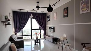 A modern living room with a sofa, a dining table, and a TV mounted on the wall.