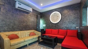 A modern living room with a beige sofa, a red sofa, and a black coffee table. - 99 Pool Villa (Pattaya)