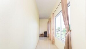 A narrow hallway with large windows and curtains, leading to a room with a small table and chair. - 99 Pool Villa (Pattaya)