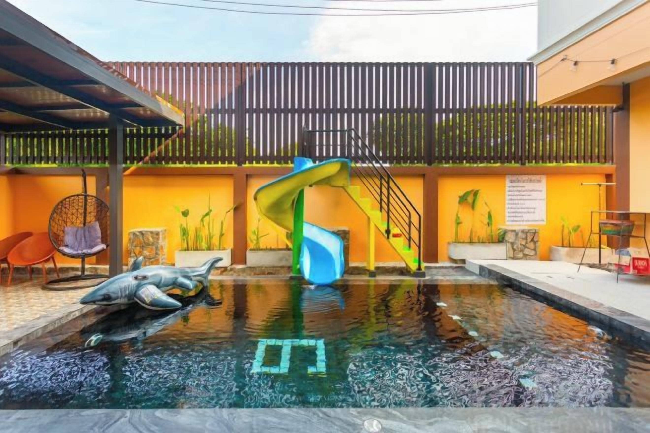 An indoor swimming pool with a slide, a dolphin sculpture, and a covered seating area.