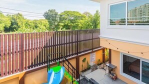 A two-story building with a balcony, a slide, and a small outdoor seating area. - 99 Pool Villa (Pattaya)
