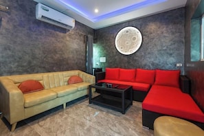 A modern living room with a beige sofa, a red sofa, and a black coffee table. - 99 Pool Villa (Pattaya)