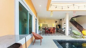 A modern living area with a pool, a dining area, and a staircase. - 99 Pool Villa (Pattaya)
