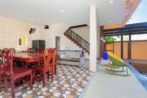 Zona pranzo con tavolo e sedie in legno, cucina con forno a microonde e una scala che conduce a un piano superiore.
