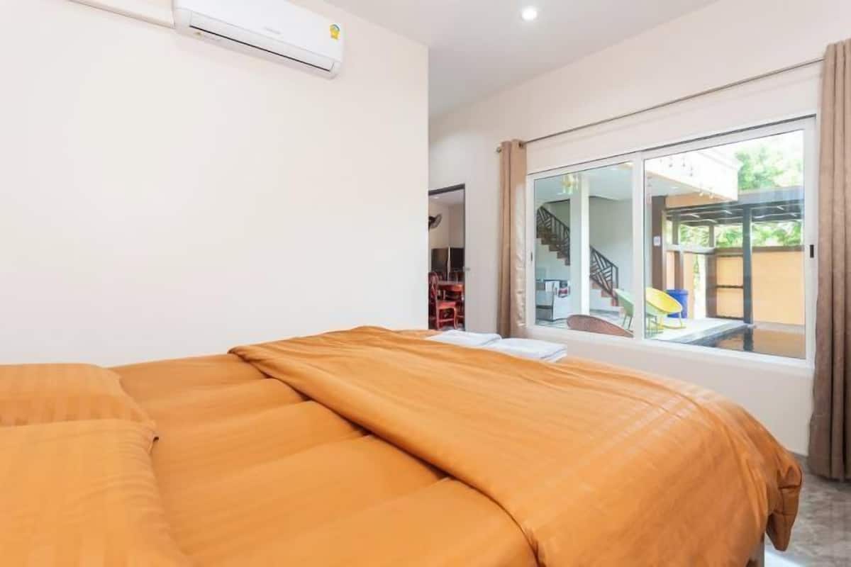 Un dormitorio con una cama grande, un equipo de aire acondicionado y vistas a una escalera y un espacio exterior a través de un ventanal corredera.
