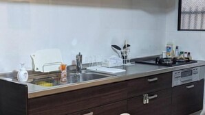 Une cuisine moderne dotée d’un évier en acier inoxydable, de meubles de rangement en bois foncé et d’un plan de travail blanc.