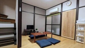 Une pièce avec un plancher en bois, un lit avec un matelas bleu, une table en bois, une télévision et une armoire.