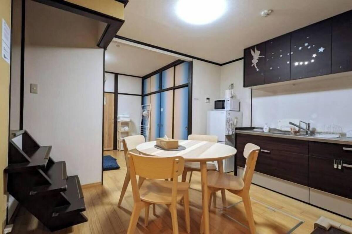 Een moderne keuken met donkere kastjes, een ronde eettafel en houten stoelen.